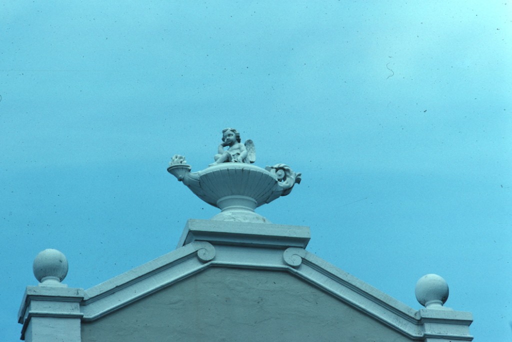 Detail van de versiering op de timpaan van de Concertzaal, een olielamp met een cherubijntje.